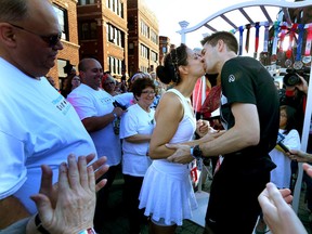 In this Oct. 11. 2015 photo, Stephanie Reinhart, centre left, kisses Mark Jockel at their wedding at the 8-mile mark during the Chicago Marathon in Chicago. The couple met two years ago through the Chicago Area Runners Association. (Nancy Stone/Chicago Tribune via AP)