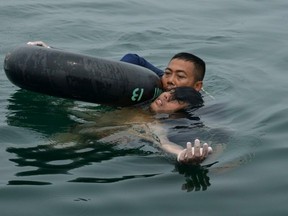 In this handout photograph released by the Indonesian Navy on Oct. 13, 2015, an Indonesian Navy diver rescues helicopter crash survivor Fransiskus Subihardayan after he was found by the search and rescue team in Lake Toba, western Sumatra island, on Oct. 13, 2015. (AFP PHOTO/INDONESIAN NAVY)