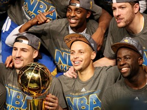 Warriors' Klay Thompson (bottom left), Stephen Curry (bottom centre) and Draymond Green (bottom right) celebrate with the Larry O'Brien NBA Championship Trophy after defeating the Cavaliers in six games during the 2015 NBA Finals in Cleveland on June 16, 2015. (Ezra Shaw/Getty Images/AFP)