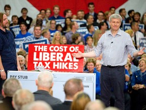 Tory leader Stephen Harper doles out cash, meant to signify the tax costs to a family under the leadership of a Liberal government, during a campaign stop Tuesday in London. (CRAIG GLOVER, The London Free Press)