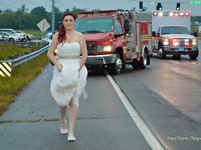 In this Oct. 3, 2015 photo provided by Marcy Martin Photography, her daughter Sarah Ray, in her wedding dress, attends to a car crash in Clarksville, Tenn. Ray's father and grandparents where in a car crash on their way to Ray's wedding reception. Ray, who is a paramedic, went to the scene to check on her relatives. (Marcy Martin Photography via AP)