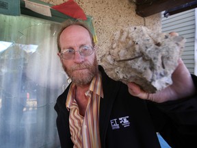 David Williamson holds a piece of concrete that some one had thrown through his front window in Edmonton, Alta., on Wednesday October 14, 2015. Perry Mah/Edmonton Sun