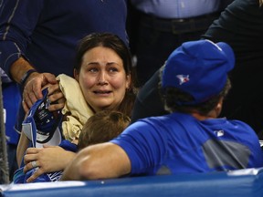 A Blue Jays fan holds her baby who was hit by spray from a beer bottle thrown during the seventh inning of the ALDS Game 5 against the Texas Rangers. (DAVE ABEL/Toronto Sun)