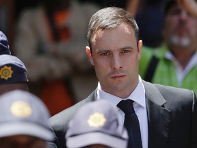 In this Friday, Oct. 17, 2014 file photo, Oscar Pistorius is escorted by police officers as he leaves the high court in Pretoria, South Africa. Pistorius is  to be released from jail Tuesday, Oct. 20, 2015 under house arrest. (AP Photo/Themba Hadebe, File)