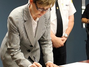 Sarnia Police Chief Phil Nelson looks on as Karen Riley, from the Ontario College of Pharmacists, signs a pledge form cementing the start of a fentanyl patch exchange program in Sarnia-Lambton. Other signatories included representatives with Sarnia Police, Lambton OPP, Lambton Public Health and the County of Lambton. (Tyler Kula/Sarnia Observer/Postmedia Network)