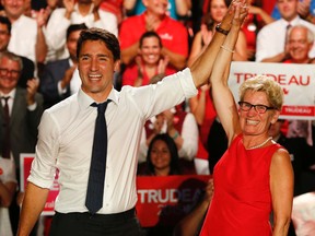 Federal Liberal leader Justin Trudeau has his hand held aloft  by  Ontario Premier Kathleen Wynne at a Liberal rally in Toronto..( Jack Boland/Postmedia Network.)