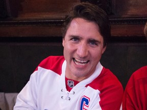 Liberal leader Justin Trudeau shows off his Montreal Canadiens jersey with the number 9, the number of former Canadiens great Maurice Richard, while watching a hockey game in a pub in Montreal on  Oct. 15, 2015. (THE CANADIAN PRESS/Paul Chiasson)