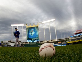 A baseball sits on the field as members of the Toronto Blue Jays watches take batting practice  baseball's American League Championship Series Thursday, Oct. 15, 2015 in  Kansas City, Mo. The Toronto Blue Jays will face the Kansas City Royals in Game 1 tomorrow. (AP Photo/Matt Slocum)
