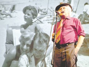 Bob Bossin shares the stage with the enlarged image of a happy family scene during his one-man play Davy The Punk, Bossin?s telling in words and song of his father?s remarkable life in the world of gambling. (Barry Kay/Special to Postmedia News)