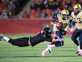 Ottawa Redblacks' defensive back Antoine Pruneau, left, tackles Winnipeg Blue Bombers' running back Da'Rel Scott causing him to drop the ball during first half CFL action in Ottawa, Friday, Oct. 16, 2015. THE CANADIAN PRESS/Adrian Wyld