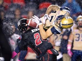 Ottawa Redblacks' linebacker David Hinds, left, tackles Winnipeg Blue Bombers' slotback Nick Moore as he tries to catch the ball during first half CFL action in Ottawa, Friday, Oct. 16, 2015. THE CANADIAN PRESS/Adrian Wyld