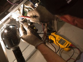 Roy Inch and Sons service technician Craig Hern uses a meter to measure the power running through a switch while conducting annual maintenance on a furnace in a Village Green Avenue home in London, Ont. on Tuesday September 8, 2015. Craig Glover/The London Free Press/Postmedia Network