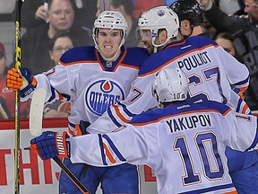 Connor McDavid celebrates his first goal against the Flames with his linemates during the second period of Saturday's game in Calgary. (Al Charest, Postmedia Network)