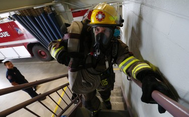 Tim Lesicky (L) watches teammate James Bates of the Toronto Pearson Combat Team go up the stairway with full bunker gear on and heavy hose line as part of his training for the Scott Firefighter Combat World Challenge in Montgomery, Alabama this Monday.  Friday October 16, 2015. Jack Boland/Toronto Sun/Postmedia Network