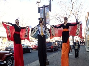 Three characters on stilts on Whyte Avenue show signs reading: Vote Monday. 
Photo by Tony Saloway