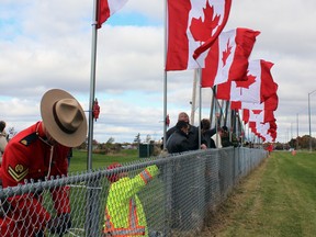 Cpl. Sean O'Brien, of the Kingston RCMP Shiprider, secures one of the 127 Canadian flags for Flags of Remembrance on Saturday. (Steph Crosier/The Whig-Standard)