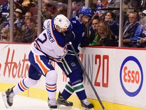 Oct 18, 2015; Vancouver, British Columbia, CAN; Edmonton Oilers forward Rob Klinkhammer (12) boards Vancouver Canucks defenseman Dan Hamhuis (2) during the first period at Rogers Arena. Mandatory Credit: Anne-Marie Sorvin-USA TODAY Sports