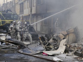 Firefighters spray water on a bakery set on fire after a small plane crashed into it in Bogota, Colombia, Sunday, Oct. 18, 2015. The plane crashed shortly after taking off from Bogota's El Dorado airport killing at least five people including the pilot and his three passengers, the city's police chief, Maj. Gen. Humberto Gatibonza Carreno said. (AP Photo/Santiago Cortez)
