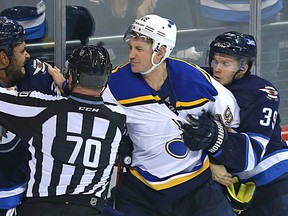 Winnipeg Jets defenceman Dustin Byfuglien swings at St. Louis Blues defenceman Jay Bouwmeester while Toby Enstrom hangs on during NHL action at MTS Centre in Winnipeg on Sun., Oct. 18, 2015. Kevin King/Winnipeg Sun/Postmedia Network