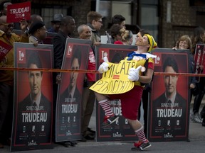 An anti-NDP demonstrator walks in front of supporters for Liberal leader Justin Trudeau before the start of the French language leaders' debate in Montreal, Quebec in this October 2, 2015, file photo. It may have been one of the longest federal election campaigns in Canadian history but it certainly hasn't been the dullest. For those who delight in the embarrassing revelation, the unexpected intervention, and the truly bizarre, it has been a campaign to savor.  REUTERS/Christinne Muschi/Files