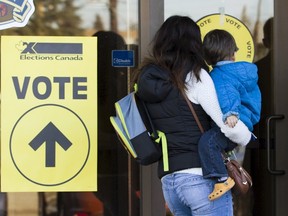 A woman holding a baby enters a polling station to vote in Calgary, Alberta, October 19, 2015.  Canadians go to the polls for a federal election on Monday.  REUTERS/Mark Blinch
