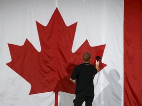 A worker steam cleans a Canadian flag in preparation for New Democratic Party leader Tom Mulcair's election night rally in Montreal, October 19, 2015. (REUTERS/Jim Young)