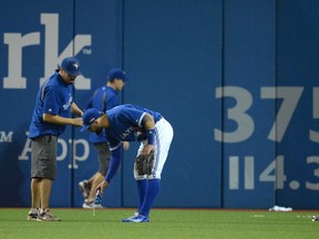 Toronto Blue Jays' centre-fielder Kevin Pillar helps the grounds crew pick up beer cans on the field after the Texas Rangers scored a controversial run during seventh inning game 5 American League Division Series baseball action in Toronto on Wednesday, Oct. 14, 2015. (THE CANADIAN PRESS/Chris Young)