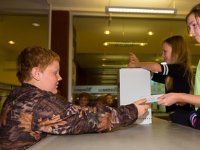 TIM MILLER/THE INTELLIGENCER
Abbey Boyle hands her ballot to Justin Carlyle, who was acting as a poll clerk as part of the Student Vote exercise at Stirling Public School on Friday. The exercise, which mimicked Monday's federal election, was designed to get youth engaged in the election process early on.