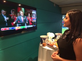 WestJet corporate box hostess Amanda Costa takes a quick look at federal election results during the Blue Jays ALCS game Monday, Oct. 19, 2015. (Joe Warmington/Toronto Sun)