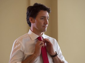 Liberal leader Justin Trudeau adjusts his tie as he waits in line to vote at a polling station in Montreal Monday, October 19, 2015. THE CANADIAN PRESS/Adrian Wyld