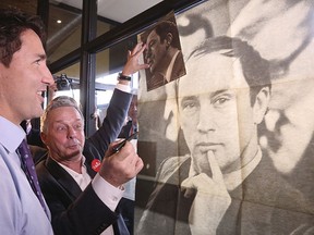 Liberal leader Justin Trudeau looks at a poster of his late father, former Prime Minister Pierre Trudeau, during a campaign stop at a coffee shop in Sainte-Therese, Quebec, Oct. 15, 2015. REUTERS/Chris Wattie