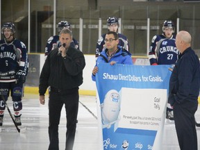 Rolly Côte of KidSport (left to right), Brian Johnston from Shaw Direct and Brian Hofferd, Assistant Coach of the Cochrane Crunch hold the tally banner that will be displayed at local games. It will record the goals to reflect the dollars that Shaw will be donating.