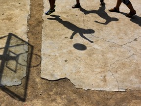 Students cast shadows as they play basketball at a playground at Dalu primary school in Gucheng township of Hefei, Anhui province, China, September 8, 2015. The school, opened in 2006 and has never acquired a legal license, may face a shutdown order from the government. There are currently over 160 students in the school, mostly "leftover children", whose parents left their hometown to earn a living, local media reported. REUTERS/Stringer