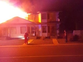 Lacombe Police Service Const. John Hubbard brings a one-year-old girl to safety on Sunday as flames billow out of her bedroom. Photo Supplied