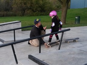 A teenager offers skateboard tips to six-year-old Peyton at a skate park in Cambridge, Ont. in a recent handout photo. A southern Ontario mom is hoping to thank an anonymous teenage boy for helping break down gender barriers for her six-year-old daughter. (THE CANADIAN PRESS/HO-Jeanean Thomas)