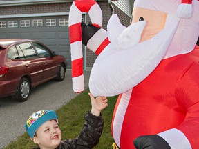 Seven-year-old Evan Leversage checks out an inflatable Santa on a neighbour's front lawn on Sunday, Oct. 18, 2015 in St. George, Ont. . (Brian Thompson/Postmedia Network)