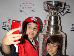 Tristan Poirier and Adrian Poirier take selfies with the Stanley Cup at Canadian Tire Centre Wednesday. (Julienne Bay/Ottawa Sun)