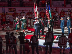 Ottawa Senators' players and New Jersey Devils', along with game officials and representatives of Canada's military, stand together at centre ice as Lyndon Slewidge leads the sold out crowd at Canadian Tire Centre in the singing of O' Canada prior to the NHL hockey game at the Canadian Tire Centre in Ottawa, Ontario on Saturday October 25, 2014. The teams were honouring fallen soldier Cpl. Nathan Cirillo. Errol McGihon/Ottawa Sun files
