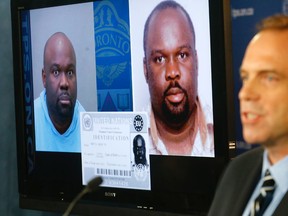 Toronto Police Det-Sgt Ian Nichol speaks to media about a fraud investigation that is linked to an FBI crime Thursday October 22, 2015. On monitor is Akohomen Ighedoise, who is alleged to be a high-ranking member of the Black Axe. (Michael Peake/Toronto Sun)