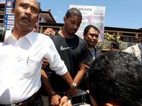 Former Austin police officer VonTrey Jamal Clark, center, is escorted by Indonesian police officers during his extradition in connection with a murder case at the regional police headquarters in Bali, Indonesia, Wednesday, Sept. 2, 2015. (AP/Firdia Lisnawati)