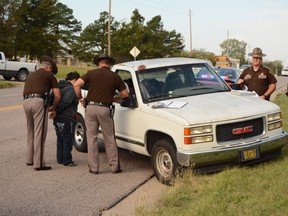 In this photo taken Wednesday, Oct. 21, 2015, Oklahoma Highway Patrol troopers Keith Teel, left, and Brian Bagwell arrest a woman on suspicion of driving under the influence after she allegedly fell out of a moving pickup truck in Ada, Okla. Authorities say a 3-year-old boy took the wheel of the pickup truck and drove it several blocks across four lanes of an Oklahoma highway after his apparently intoxicated mother fell out. (Randy Mitchell/The Ada News via AP)