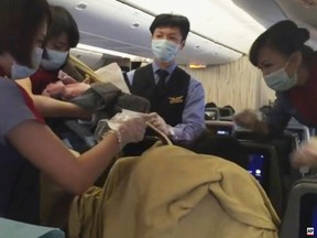In an image from AP video, a member of the plane's crew holds up a newborn after Dr. Angelica Zen, who is obscured at lower right, delivered the baby on a China Air flight from Taiwan on Oct. 7, 2015. A passenger had gone into labour, and the flight was diverted to Alaska. Mother and newborn daughter left for a hospital, and the flight continued on to Los Angeles. (Edmund Chen/AP Video via AP Photo)