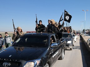 In this file photo released on May 4, 2015, on a militant website, which has been verified and is consistent with other AP reporting, Islamic State militants pass by a convoy in Tel Abyad, northeast Syria. The Islamic State rakes in up to $50 million a month from selling crude from oilfields under its control in Iraq and Syria, part of a well-run oil industry that U.S. diplomacy and airstrikes have so far failed to shut down, according to Iraqi intelligence and U.S. officials. (Militant website via AP, File)