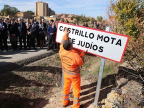 Officials look at an employee setting up a road sign reading the new name of Spanish village "Castrillo Mota de Judios" which means "Castrillo Mound of Jews"  at the entrance of Castrillo Mota de Judios, near Burgos on October 23, 2015. (AFP PHOTO/CESAR MANSO)