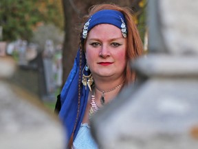 Tim Miller/The Intelligencer
Maurene Rose, a paranormal investigator with The Eastern Ontario Truth, looks through an old grave marker at the Belleville Cemetery on Thursday. Rose knows a great many stories about Belleville's paranormal history.