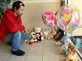 Denell Handsor looks at a collection of stuffed animals and balloons on Friday October 23, 2015 in the lobby of an Arbour Glen Cres. apartment building where a 6-year-old girl was stabbed the day before. (MORRIS LAMONT, The London Free Press)
