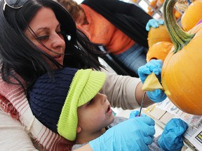 Lisa Headrick and her three-year-old son Ian carve a pumpkin at Fiery Faces' annual Family Fun Day at DeGroot's Nurseries in Sarnia Saturday. The kids' event helped kick off the annual Fiery Faces fundraiser that features hundreds of lit jack-o'-lanterns on display. Tyler Kula/Sarnia Observer/Postmedia Network