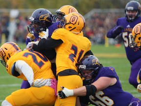 Laurier Golden Hawk Dillon Campbell seemingly invisibles against Golden Gaels Chris Mackey,James Donald, and Mike Moore at their game in Kingston, Ont. on Saturday October 24, 2015 Queen's fell to Laurier 49-26. Steph Crosier/Kingston Whig-Standard/Postmedia Network