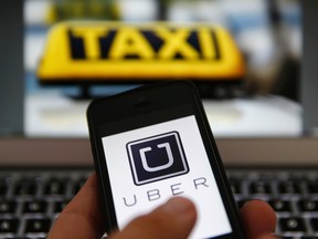 A file illustration picture shows the logo of car-sharing service app Uber on a smartphone next to the picture of an official German taxi sign in Frankfurt, September 15, 2014. REUTERS/Kai Pfaffenbach/Files