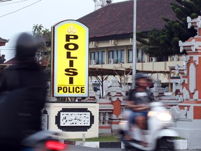 Motorcyclists pass by Denpasar's police station where Rajendra Sadashiv Nikalje is detained, in Bali, Indonesia, Monday, Oct. 26, 2015. Nikalje, known in India as “Chotta Rajan,” an alleged mafia boss in his homeland was on the Interpol’s most wanted list for two decades, said Bali police spokesman Heri Wiyanto. (AP Photo/Firdia Lisnawati)
